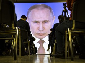 In this file photo taken Thursday, March 1, 2018, journalists watch as Russian President Vladimir Putin gives his annual state of the nation address in Manezh in Moscow, Russia.