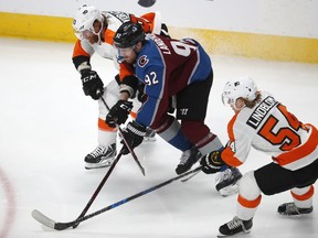 Colorado Avalanche left wing Gabriel Landeskog, center, tries to move the puck down the ice as Philadelphia Flyers right wing Jakub Voracek, top and, left wing Oskar Lindblom defend during the first period of an NHL hockey game Wednesday, March 28, 2018, in Denver.