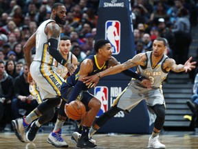 Denver Nuggets guard Gary Harris, center, drives between Cleveland Cavaliers forward LeBron James, left, and guard George Hill during the first half of an NBA basketball game Wednesday, March 7, 2018, in Denver.
