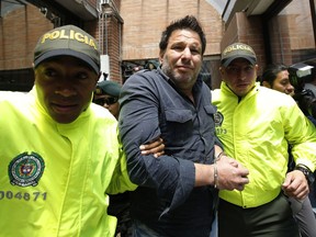 Police escort Cuban suspect Raul Gutierrez to court where a judge will rule on prosecutors' request he be held on terrorism and conspiracy charges in Bogota, Colombia, Thursday, March 15, 2018. Gutierrez is suspected of plotting to kill American diplomats in the name of the Islamic State.