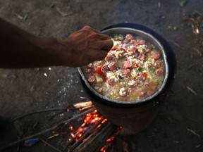 In this Feb. 22, 2018 photo, Venezuelan migrants cook rice with sausage in Cucuta, Colombia, on the border with Venezuela. On this night more than six pots of rice and sausage were prepared by the migrants, who spent the night under a growth of trees next to the Simon Bolivar International bridge.