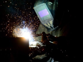 The economy added 15,400 net new jobs last month and the unemployment rate edged down to 5.8 per cent -- but the gains were due to a surge in part-time work that offset a decline in full-time positions. A welder fabricates a steel structure at an iron works facility in Ottawa on Monday, March 5, 2018.