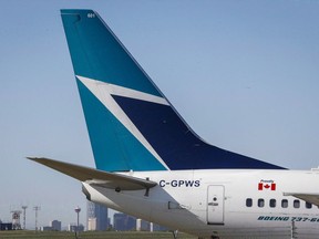 The tail of a WestJet plane is seen dwarfing the Calgary skyline before the airline's annual meeting in Calgary on May 3, 2016. A WestJet flight attendant says rules that effectively pay starting workers less than minimum wage because they're compensated only for time in the air is helping a union drive at Canada's second-largest airline.THE CANADIAN PRESS/Jeff McIntosh