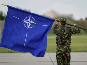 A Romanian serviceman furls the NATO flag at the Mihail Kogalniceanu air base in Romania, Wednesday, June 14, 2017. When it comes to surprises, Russia has been scoring more points than NATO.That is the frank assessment of Col. Ilmars Lejins, one of the top military commanders in Latvia, where Canada is currently leading a multinational NATO battlegroup charged with checking Russian aggression in Eastern Europe.