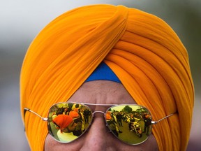 Members of the Sikh Motorcycle Club are reflected in a fellow member's sunglasses during the annual Vaisakhi parade in Vancouver on April 16, 2016. Alberta is to allow turban-wearing Sikhs to ride motorcycles without helmets. The exemption to the province's Traffic Safety Act that will apply to adult motorcycle drivers and passengers is to go into effect on April 12. Transportation Minister Brian Mason says the change follows a request from the Sikh community.