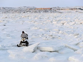 A snowmobiler makes his way through the ice heaves in Frobisher Bay in Iqaluit, Nunavut on Wednesday, December 10, 2014. The federal auditor general says Nunavut isn't doing enough to get ready for climate change. In his report released today, James McKenzie says the effects of climate change are increasingly visible across the territory.