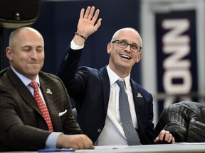 Dan Hurley waves as he is introduced as the new NCAA college basketball head coach at the University of Connecticut, Friday, March 23, 2018, in Storrs, Conn. Hurley, who coached Rhode Island into the NCAA Tournament the past two seasons, replaces Kevin Ollie, who was fired earlier this month. At left is UConn Athletic Director David Benedict.