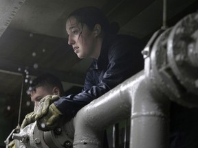 In this April 26, 2017 photo U.S. Navy Ensign Megan Stevenson, of Raymond, Maine takes a rest after working with other U.S. Navy officers to patch high-pressure leaking pipes inside a replica of a submarine engine room during a damage control training exercise at the Naval Submarine School, in Groton, Conn. The Navy began bringing female officers on board submarines in 2010, followed by enlisted female sailors five years later. Their retention rates are on par with those of men, according to records obtained by The Associated Press.