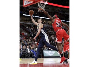 Denver Nuggets' Nikola Jokic, left, scores past Chicago Bulls' Noah Vonleh during the first half of an NBA basketball game Wednesday, March 21, 2018, in Chicago.