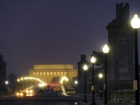 Traffic moves across the Memorial Bridge with the Lincoln Memorial in the background as snow begins to fall before daybreak in Washington, Wednesday, March 21, 2018.