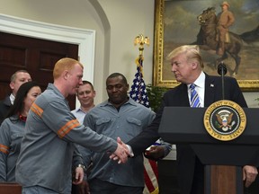 President Donald Trump reaches out to shake the hand of Dusty Stevens, a superintendent at Century Aluminum Potline, during an event in the Roosevelt Room of the White House in Washington, Thursday, March 8, 2018. Trump signed two proclamations, one on steel imports and the other on aluminum imports.