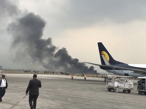 Smoke rises after a passenger plane from Bangladesh crashed at the airport in Kathmandu, Nepal, Monday, March 12, 2018. A passenger plane carrying 71 people from Bangladesh crashed and burst into flames as it landed Monday in Kathmandu, Nepal's capital, killing dozens of people with others rushed to area hospitals, officials said.