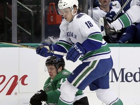 Vancouver Canucks right wing Jake Virtanen (18) knocks Dallas Stars center Mattias Janmark (13) to the ice as the two compete for control of the puck in the first period of an NHL hockey game in Dallas, Sunday, March 25, 2018.