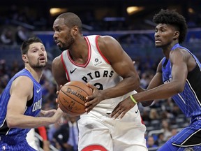 Toronto Raptors' Serge Ibaka, center, looks for a way to the basket as he gets between Orlando Magic's Nikola Vucevic, left, and Jonathan Isaac, right, during the first half of an NBA basketball game, Tuesday, March 20, 2018, in Orlando, Fla.