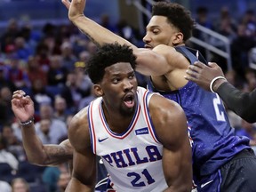 Philadelphia 76ers' Joel Embiid (21) looks to pass the ball as he is defended by Orlando Magic's Khem Birch, right, during the first half of an NBA basketball game, Thursday, March 22, 2018, in Orlando, Fla.