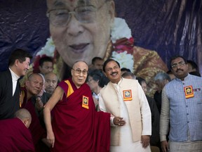 Tibetan spiritual leader the Dalai Lama holds hand with junior Indian Minister for Culture and Tourism Mahesh Sharma at an event marking the beginning of the 60th year of the spiritual leader's exile in India, in Dharmsala, India, Saturday, March 31, 2018. The Dalai Lama thanked India for giving shelter to him and said Tibetans have turned their unfortunate circumstances into a path of enlightenment by reviving their spirit and influence wherever they are.