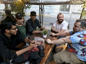 In this March 20, 2018 photo, Guido Nunez-Mujica, right, meets for the firs time with fellow Venezuelans who he helped leave Venezuela, Daniel Klie, left, and Elias Martinez, third from left, as Elias' girlfriend Elizabeth Vieria and Nunez-Mujica' American husband Tom Japhet join them at a bar in Santiago, Chile. Nunez-Mujica, who works in the U.S., is helping resettle a group of young Venezuelans trying to retrace his own immigrant's journey to a better future.