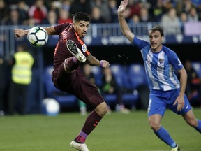 Barcelona's Suarez fights for the ball against Malaga's Ignasi Miquel during a Spanish La Liga soccer match between Malaga and Barcelona in Malaga, Spain, Saturday, March 10, 2018.