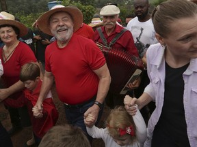 Brazil's former President Luiz Inacio Lula da Silva walks with supporters during a rally on a farm in Nova Erechim in southern Brazil, Sunday, March 25, 2018. The former leader is leading polls for October's presidential election, but he is likely to be barred from running and  judges could order him early as Monday to begin serving his sentence on a corruption conviction.