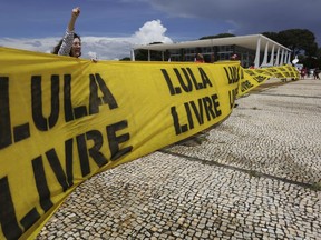 Supporters of Brazil's former President Luiz Inacio Lula da Silva hold up a banner that reads in Portuguese "Free Lula!" and shout slogans in his support outside the Supreme Court in Brasilia, Brazil, Thursday, March 22, 2018. Da Silva launched a book last week in which he says he is "ready" to go to jail and serve a 12-year and one-month sentence on a corruption charge conviction.