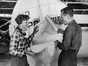 In this undated photo, aviator Amelia Earhart, left, and navigator Fred Noonan pose with a map of the Pacific Ocean showing the planned route of their round-the-world flight.