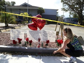 FILE - In this Thursday, Sept. 14, 2017, file photo, Janice Connelly of Hollywood, sets up a makeshift memorial in memory of the senior citizens who died in the heat at The Rehabilitation Center at Hollywood Hills, Fla. The U.S. National Hurricane Center says Monday, March 12, 2018, that the death toll from Hurricane Irma's catastrophic rampage across the Caribbean and the southeastern U.S. has risen to 44 fatalities directly caused by its strong winds and heavy rains. An additional 85 fatalities were indirectly linked to the storm. Fourteen people died at the nursing home.