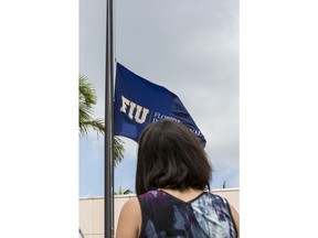 A Florida International University student observes a moment of silence for the victims of the bridge collapse at the school four days earlier, as the school flag flies at half-staff on the campus, Monday, March 19, 2018, in Miami.