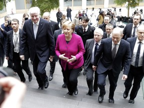 Bavarian governor and head of the Christian Social Union Horst Seehofer, German Chancellor and head of the Christian Democratic Union, Angela Merkel, and Hamburg mayor and acting chairman of the Social Democratic Party Olaf Scholz, from left, arrive for a press conference on the new German government in Berlin, Germany, Monday, March 12, 2018.