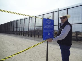 This photo provided by the New Mexico State Land Office shows New Mexico Land Commissioner Aubrey Dunn installing a sign along the U.S.-Mexico border to indicate the land belongs to the state Tuesday, March 6, 2018, near Santa Teresa, N.M. New Mexico's top land manager posted signs along the U.S.-Mexico border aimed at blocking border patrol operations on a one-mile stretch of state trust land over concerns that the federal government is not compensating the state for using the land.