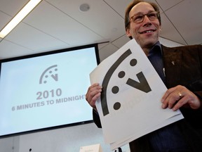 FILE - In this Jan. 14, 2010 file photo, Lawrence Krauss, co-chair of the Bulletin of Atomic Scientists Board of Sponsors poses with a graphic image of the "Doomsday Clock" a during a news conference, in New York. Krauss, an Arizona State University physics professor, has been suspended from his job following allegations of groping, ogling and other sexual misconduct incidents. The school confirmed Wednesday, March 7, 2018, that Krauss is on paid leave and prohibited from campus while a review is conducted.