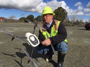 In this photo taken Jan. 26, 2018, Mike Moy, an assistant plant manager for Lehigh Hanson Cement Group, inspects a Kespry drone he uses to survey inventories of rock, sand and other building materials at a mining plant in Sunol, California. Robots are coming to a construction site near you. Tech startups are developing self-driving bulldozers, survey drones and bricklaying robots to help the construction industry boost productivity, speed and safety as it struggles to find enough skilled workers.