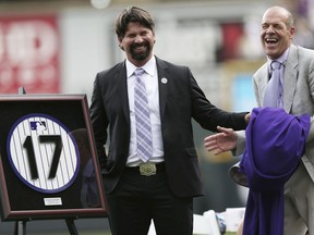 FILE - In this Aug. 17, 2014, file photo, retired Colorado Rockies first baseman Todd Helton, left, jokes with co-owner Charlie Monfort after a ceremony at which Helton's number was retired before the Rockies playing the Cincinnati Reds in a baseball game in Denver. Helton now regularly drives his two daughters to school or activities back home in Tennessee, a huge life change for Colorado's former All-Star first baseman. In fact, a daunting and overwhelming adjustment initially. "It was hardest thing I've ever done in my life," Helton shared.