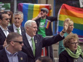Vice President Mike Pence and his mother Nancy Pence Fritsch, right, wave while walking in the St. Patrick's Day parade Saturday, March 17, 2018, in Savannah, Ga.  Crowds behind barricades across the street cheered and chanted "U-S-A" as Pence waved and gave a thumbs up sign. There were also a few protesters who followed Pence throughout the parade.