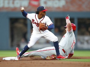 Atlanta Braves second baseman Ozhaino Albies, left, throws to first after the force-out of Philadelphia Phillies' Rhys Hoskins, right, in the first inning of a baseball game, Saturday, March 31, 2018, in Atlanta.