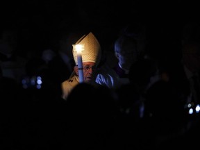Pope Francis holds a candle as he presides over a solemn Easter vigil ceremony in St. Peter's Basilica at the Vatican, Saturday, March 31, 2018.