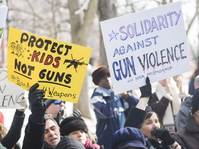 People hold up signs during a 'March of Our Lives' rally to show solidarity with the U.S. gun control movement in Montreal, Saturday, March 24, 2018.