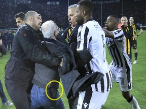 PAOK owner, businessman Ivan Savvidis approaches Vassilis Dimitriadis as his bodyguard and PAOK's players try to stop him during a Greek League soccer match between PAOK and AEK Athens in the northern Greek city of Thessaloniki, Sunday, March 11, 2018.