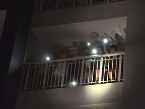 In this image taken from video, residents at a condominium use mobile phones flash to call for help following a fire in Ho Chi Minh City, Vietnam, Friday, March 23, 2018. The fire killed over a dozen people, most of them died of suffocation or jumping from high floors. (VnExpress via AP)