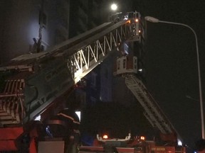 In this image taken from video, cranes are used to rescue people from a condominium complex during a fire in Ho Chi Minh City, Vietnam, Friday, March 23, 2018. The fire killed over a dozen people, most of them died of suffocation or jumping from high floors. (VnExpress via AP)