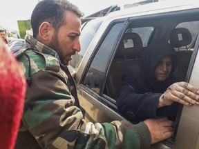 This photo released by the Syrian official news agency SANA, shows a Syrian government forces soldier, left, helping a civilian who fled from fighting between the Syrian government forces and insurgents, near Hamouria in eastern Ghouta, a suburb of Damascus, Syria, Saturday, March. 17, 2018. Government airstrikes on a rebel-held town east of the capital Damascus killed dozens and wounded scores on Friday, opposition activists said, as thousands of people left the besieged areas known as eastern Ghouta. (SANA via AP)