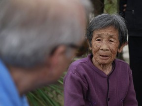 In this Thursday, March 15, 2018 photo, My Lai massacre survivor Do Thi Chi speaks to U.S. army photographer Ron Haeberle in My Lai, Vietnam. More than a thousand people are marking 50th anniversary of the My Lai massacre, using the event to talk of peace and cooperation instead of hatred.
