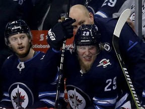 Jets forward Patrik Laine, right, grimaces in pain on the bench after blocking a shot against the Los Angeles Kings during the second period of their game in Winnipeg on Tuesday night.