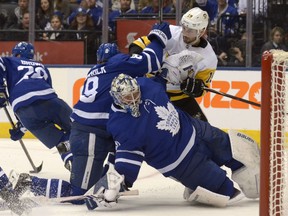 Pittsburgh Penguins centre Derick Brassard crashes into Maple Leafs goaltender Frederik Andersen and is shoved out of the crease by defenceman Connor Carrick during the third period of their game in Toronto on Saturday night.