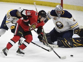 Ryan Dzingel of the Senators makes his way past the Buffalo Sabres' Brendan Guhle as goaltender Robin Lehner eyes the puck during second period NHL action in Ottawa on Thursday night.