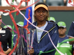 Naomi Osaka, of Japan, poses with her trophy as streamers fall after defeating Daria Kasatkina, of Russia, in the women's final at the BNP Paribas Open tennis tournament, Sunday, March 18, 2018, in Indian Wells, Calif. Osaka won 6-3, 6-2.