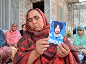 Ranjit Kaur holds a portrait of her son Tajinder Singh, one of the 38 Indian workers whose bodies were found buried northwest of Mosul, in Shiyalka village in the northern Indian state of Punjab, Tuesday, March 20, 2018.