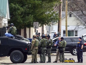 In this Monday, March 5, 2018 photo, the Terre Haute Police Department Special Response Team talk near the house with the armed suspect during a standoff in Terre Haute, Ind. A police standoff entered its second day Tuesday outside a home where a shooting suspect is holed up.