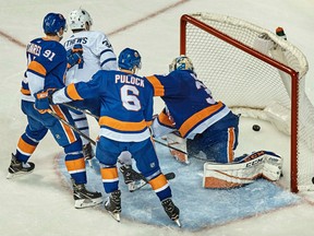 Toronto Maple Leafs' Auston Matthews scores the winning goal in between a group of Islanders players during the third period of their game on Friday night in New York.