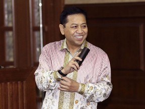 Former speaker of Indonesia's parliament Setya Novanto, center, smiles as he enters the court room after a break during his hearing at the Corruption Cases Court in Jakarta, Indonesia, Thursday, March 29, 2018. The top Indonesian politician was accused of involvement in a conspiracy of dozens of officials who used the introduction of an electronic ID system to steal more than $170 million of public money.