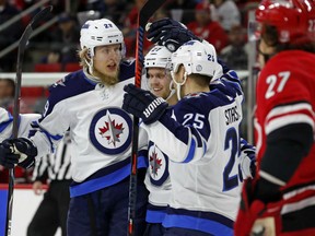 Patrik Laline, left, of the Winnipeg Jets, is congratulated by teammates Nikolaj Ehlers, centre, and Paul Stastny, after scoring one of his two goals against the Carolina Hurricanes in NHL action Sunday in Raleigh, N.C. Laline also assisted on the game-winner in a 3-2 Jets' victory.